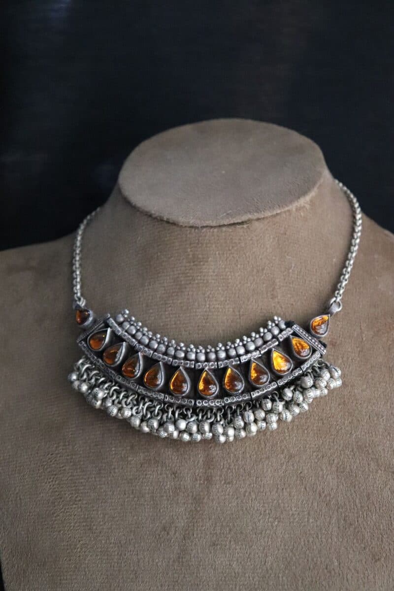A silver heritage bib necklace set with amber-toned stones